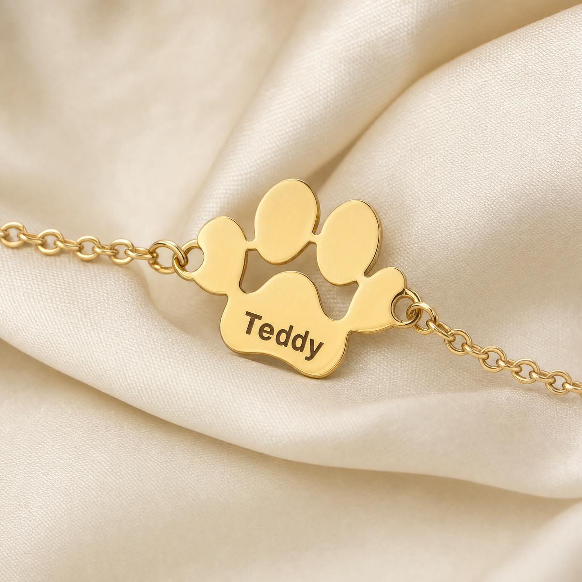Gros plan sur une patte gravée Teddy du bracelet Câline en or