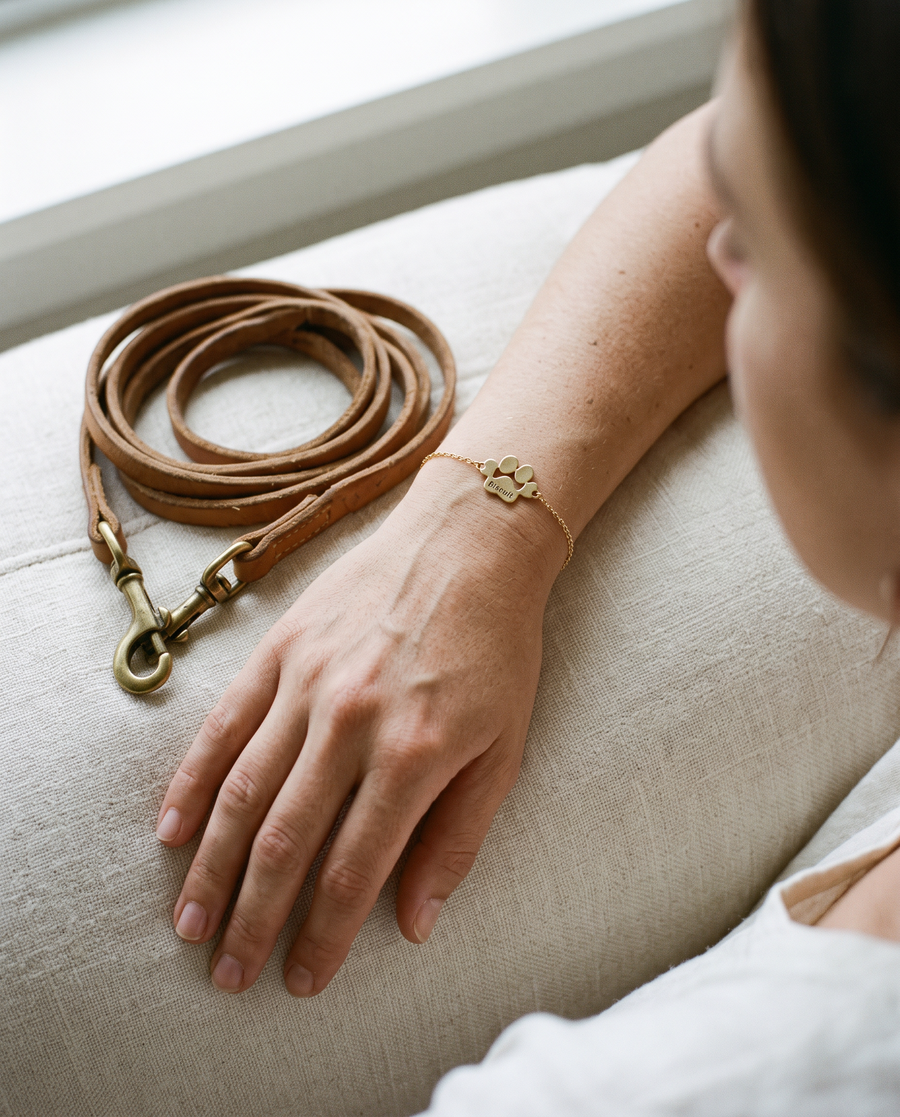 Bracelet patte or gravé Biscuit au poignet, à côté de la laisse en cuir de son chien