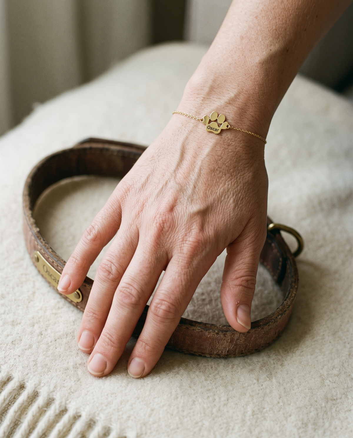 Main d'une femme portant un bracelet patte gravé Oscar, posée sur le vieux collier de son chien
